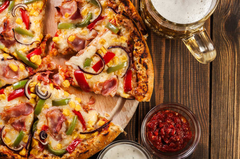 木桌上美味的玉米披萨和辣椒