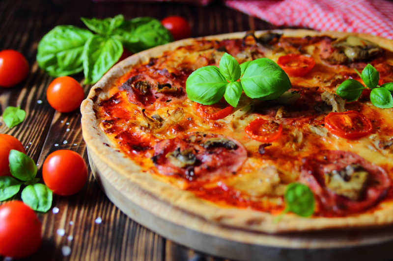 木桌上的火腿披萨和小西红柿