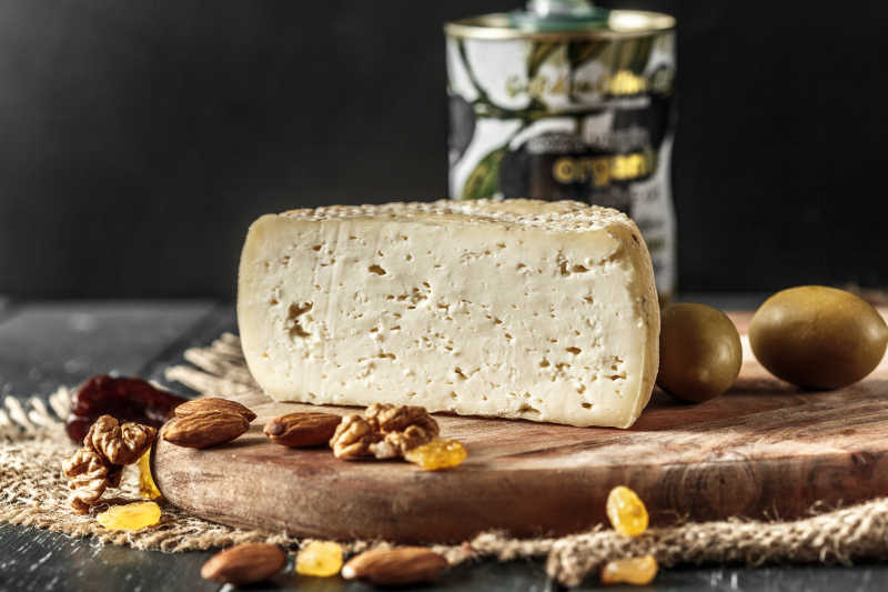 木桌上的奶酪和散落桌板上的坚果和浆果