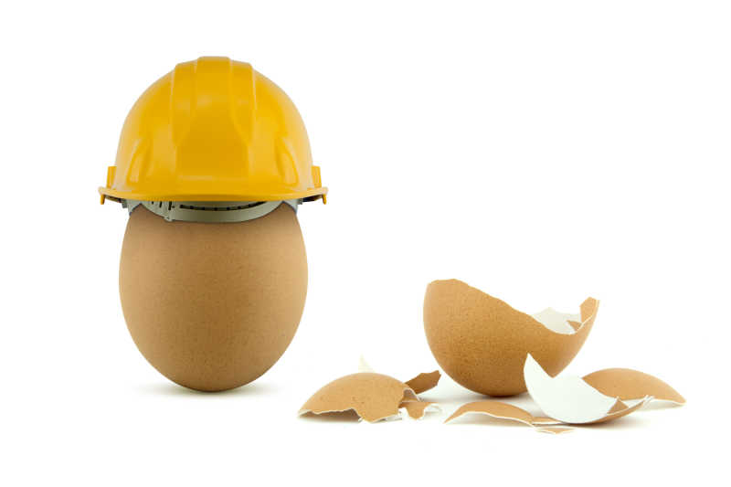 安全概念图片-白色背景下鸡蛋的状态提现了安全帽的安全概念素材-高清