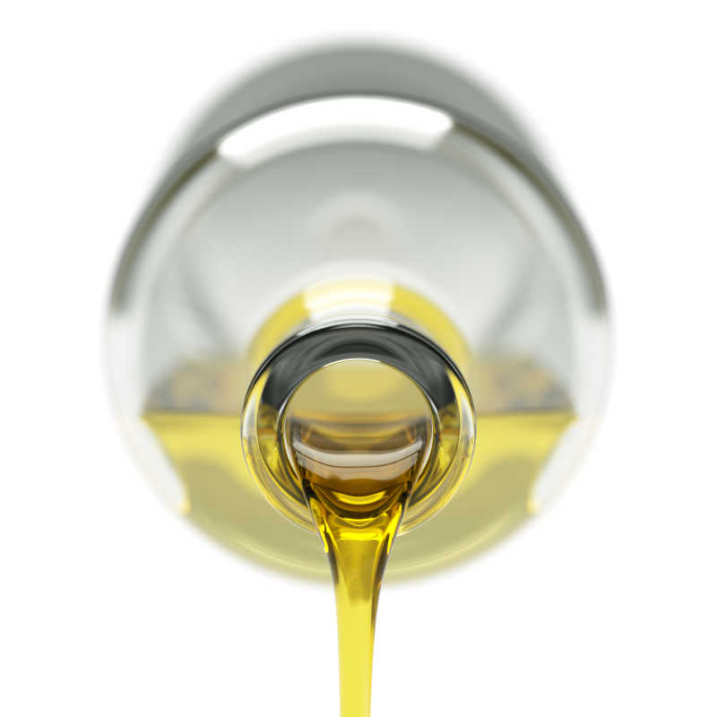 白色背景下玻璃瓶里流出的橄榄油