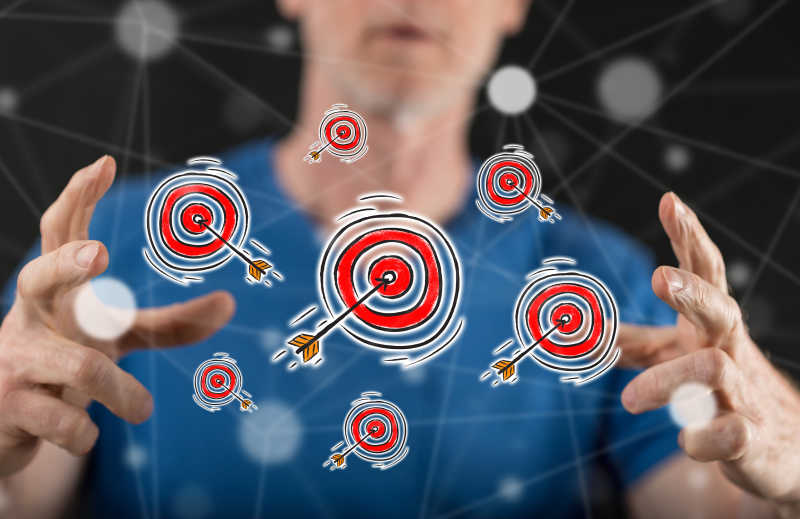 黑色背景下商人手中的飞镖正中靶心带来的业务目标概念