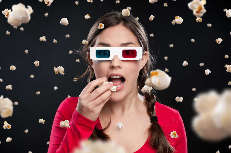 爆米花飘落背景中3D影院吃爆米花的女孩