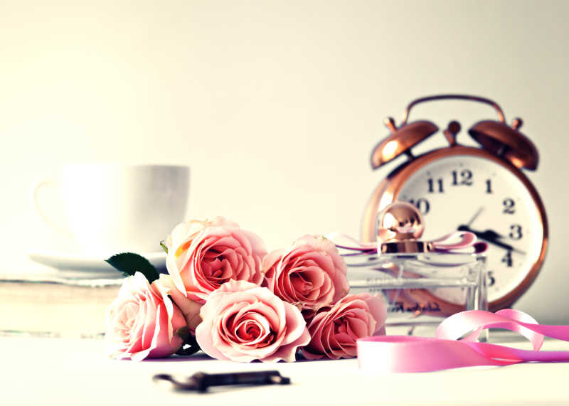 桌上摆放的闹钟咖啡杯和玫瑰花