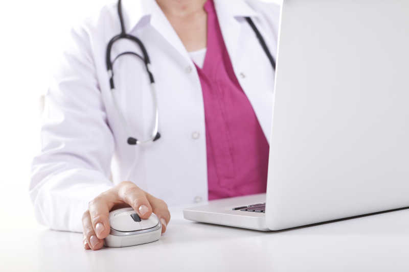 白色背景下穿工作服的医生在电脑前工作