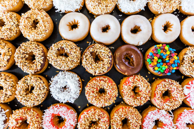 黑色桌面上的排列整齐的各色甜甜圈