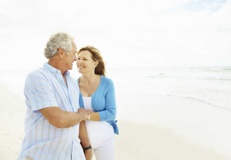 在海滩上散步的一对老夫妇相视而笑