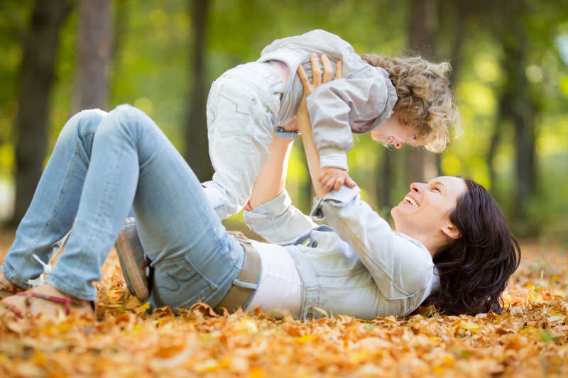 快乐的家庭在秋天户外公园模糊的背景下玩耍