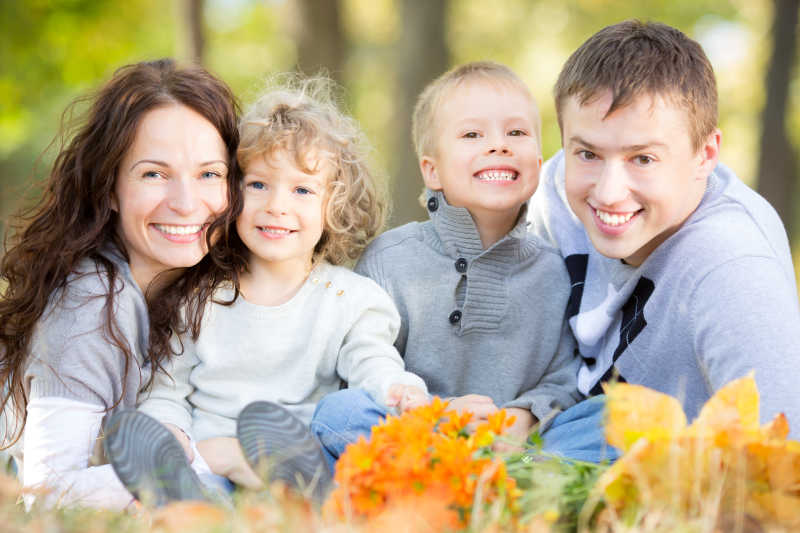 在模糊的树叶背景下快乐的家庭在秋天的公园野餐