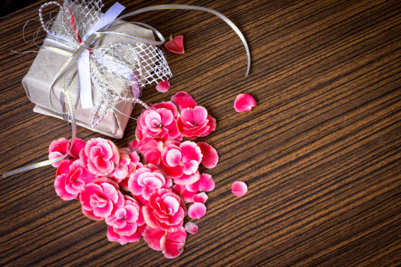 从木制餐桌上的花瓣和瓦伦丁日的背景