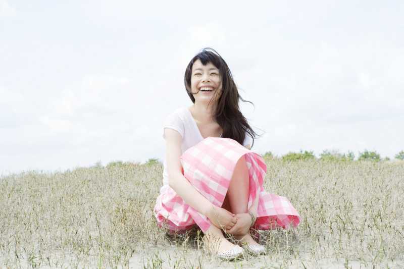 穿着连衣裙坐在沙滩上的美女