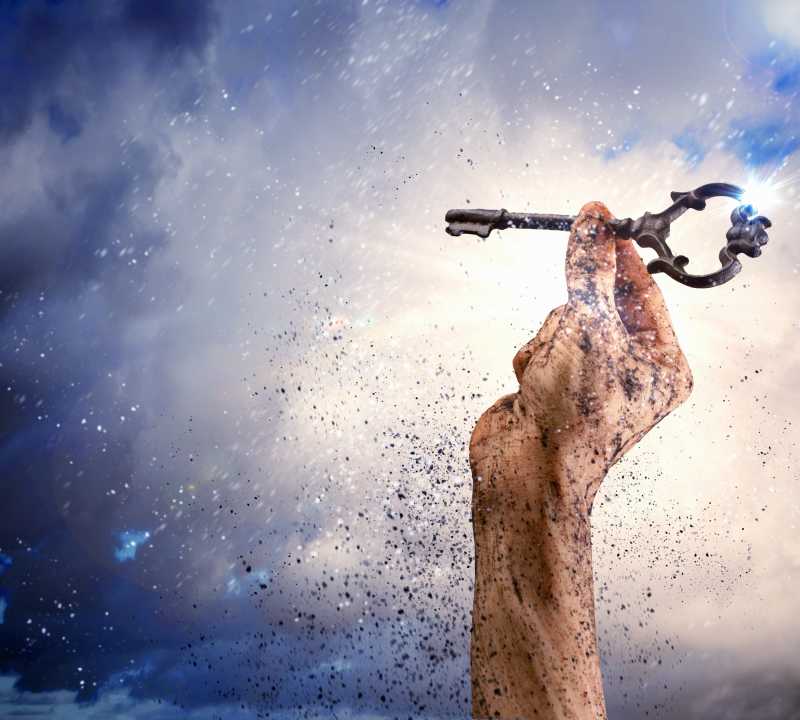 深蓝天空背景下拿着钥匙的手