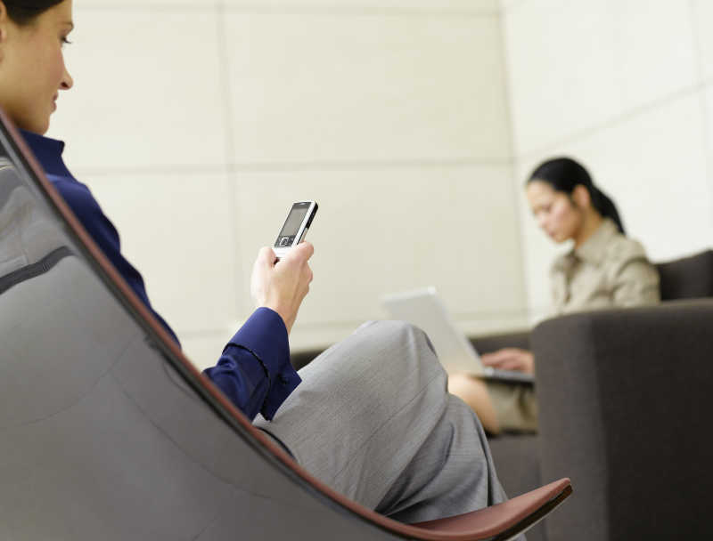 看着手机与电脑的女商人