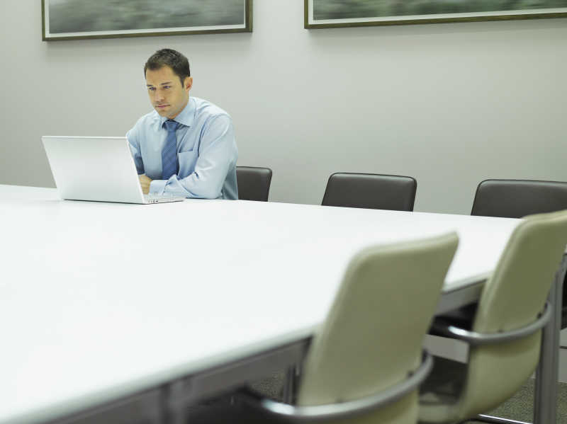 会议室里看着笔记本电脑的男性商人