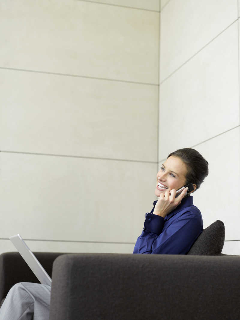 坐在沙发上打电话微笑的商人