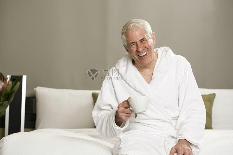 坐着的拿着茶杯笑的十分开心的中年人