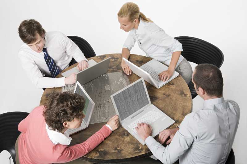 看着电脑相互交谈的商人