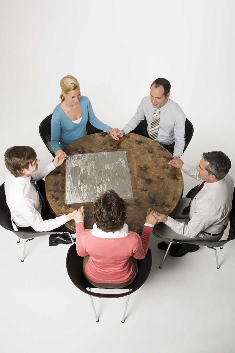 圆桌旁的手牵手的商人