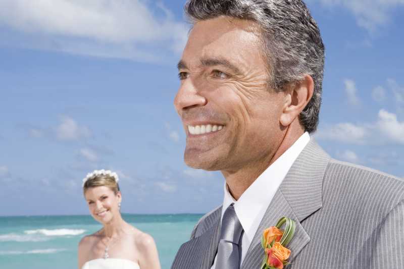 中年新郎开心的走在沙滩上