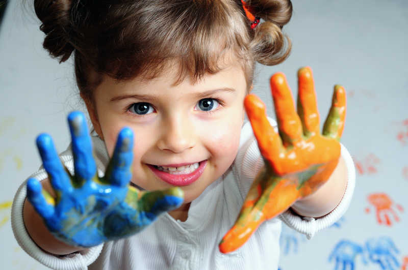 双手沾满彩色油漆的快乐的女孩