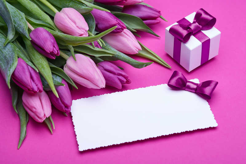 一束未开的郁金香和礼盒旁边的白色卡片