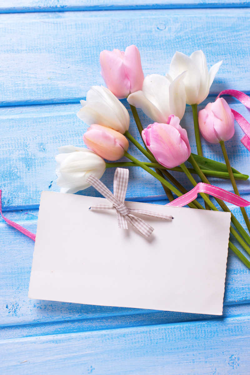美丽的粉色和白色的郁金香放在空白的卡片旁边