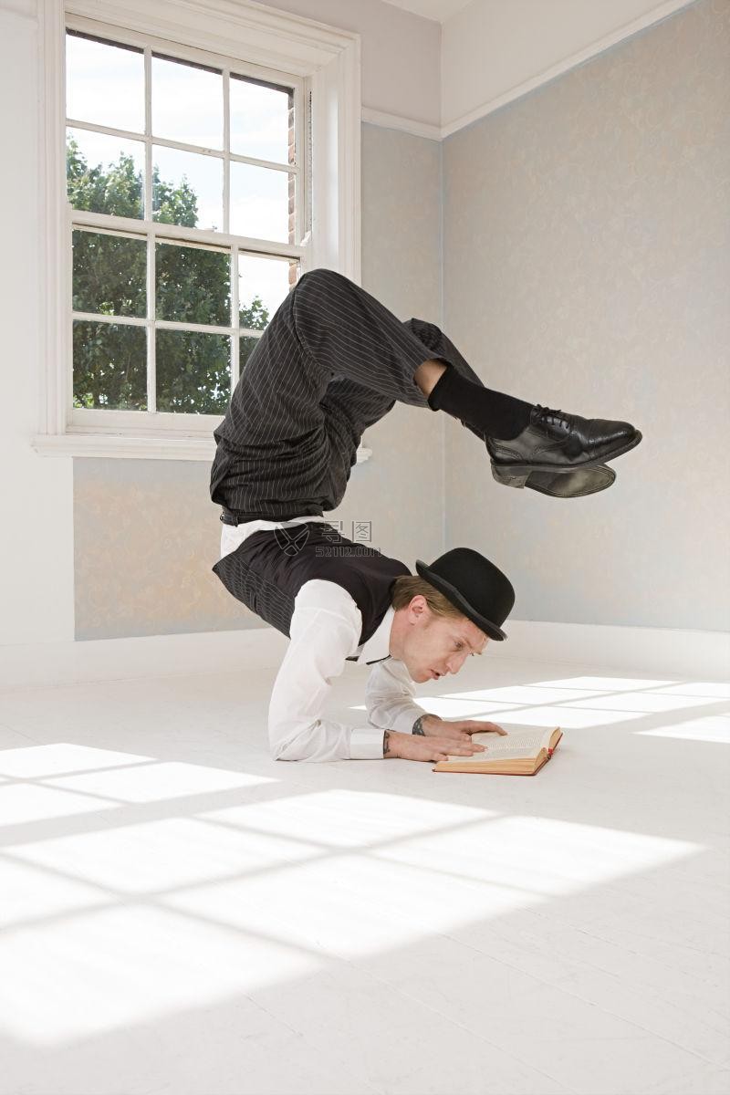 在白色地板上锻炼腰腹柔韧性的男演员在看书
