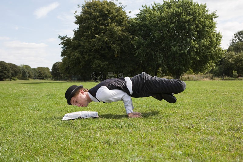 单手撑地读报纸的男人