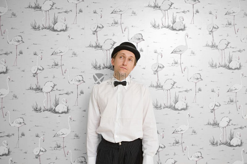 火烈鸟壁纸背景前的戴圆顶礼帽打着领结的男子