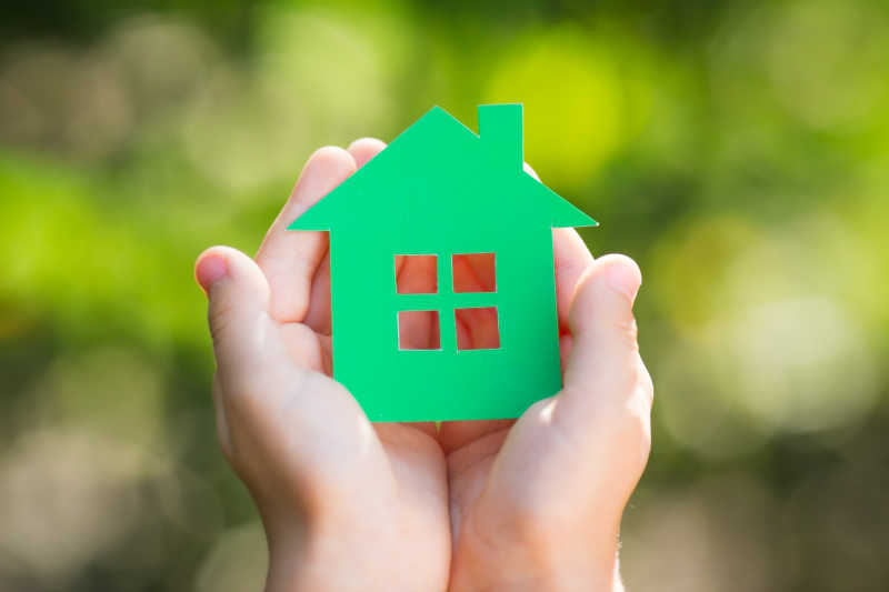 双手捧着绿色剪纸房子的孩子