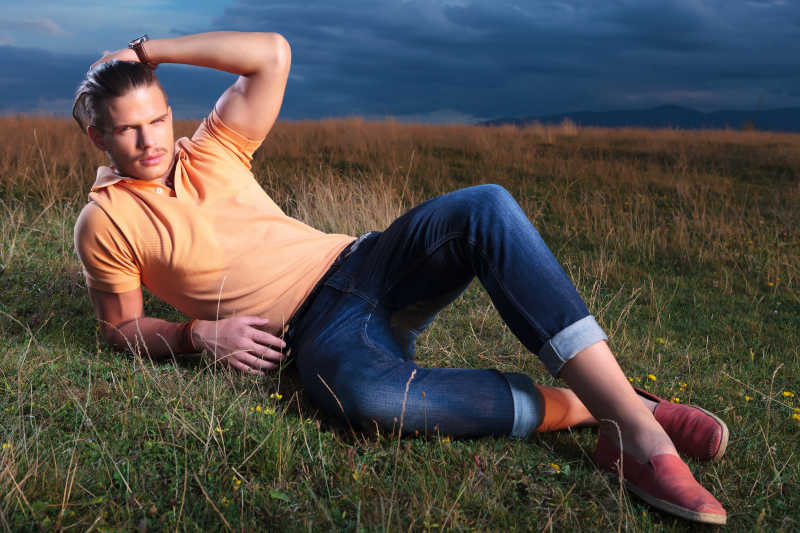 穿着休闲的年轻男人半躺在草地上