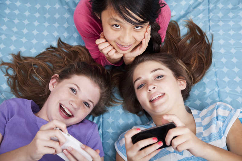 女孩躺在床上拿着手机玩