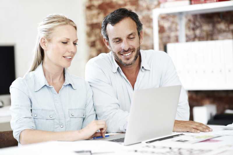 两个微笑的人在看笔记本