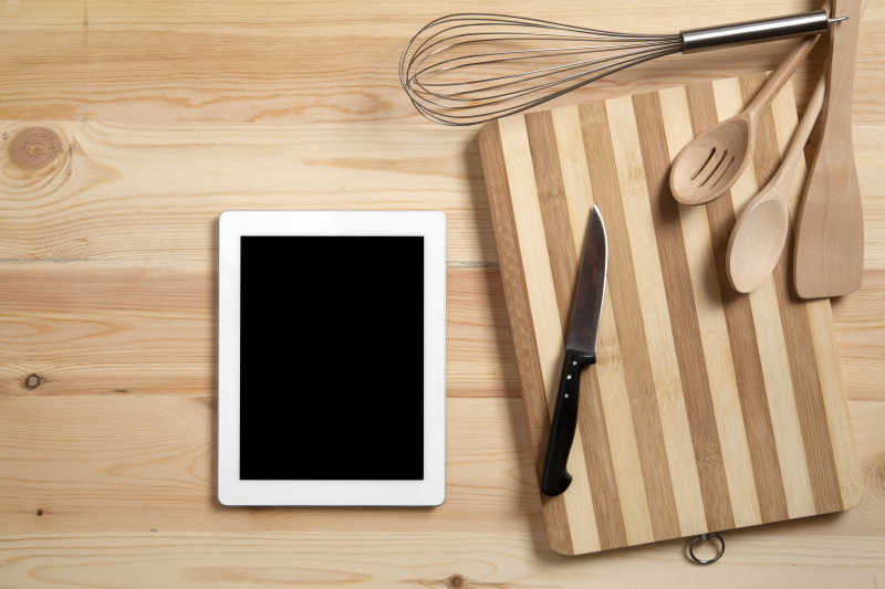 木制桌上数码平板旁边的厨房用具
