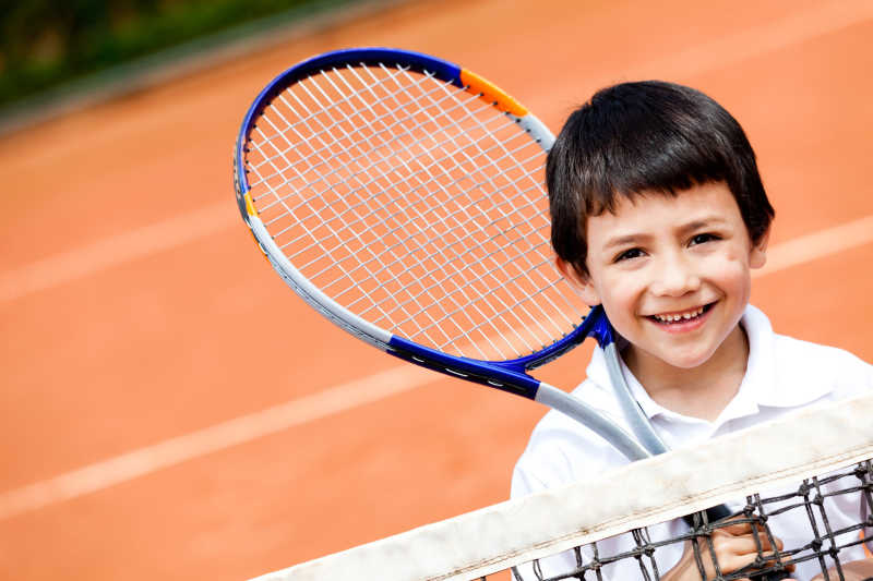 拿着网球拍微笑的小男孩