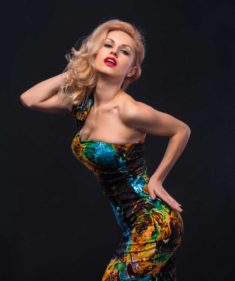 黑色背景下穿着抹胸裙摆着姿势的的女人