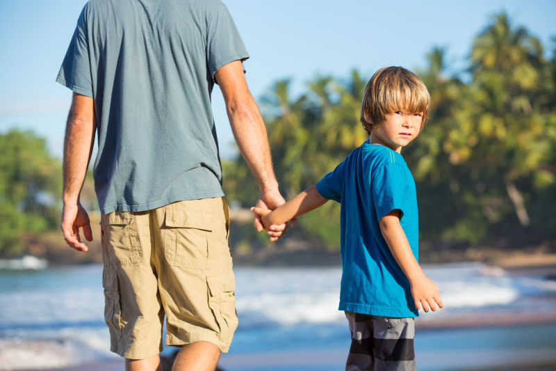 快乐的爸爸和儿子在沙滩上散步