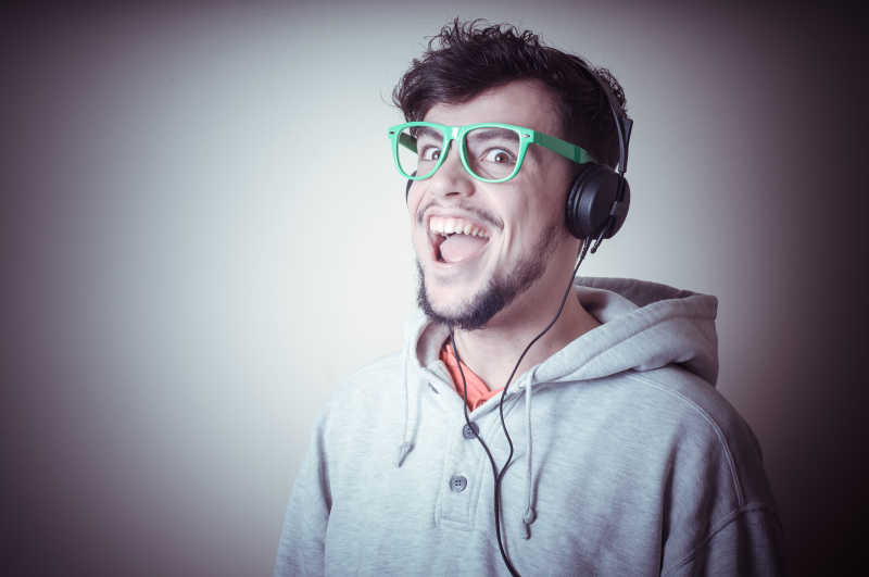 灰色背景下戴耳机的穿运动衫男子