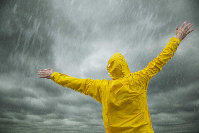 暴风雨时张开双手站在雨中的人