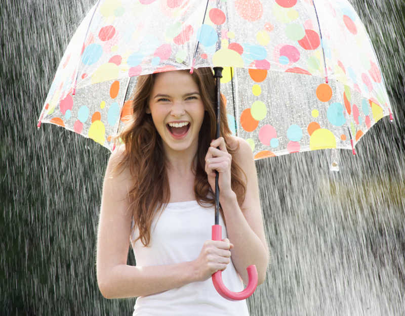 雨中撑着雨伞的年轻女孩