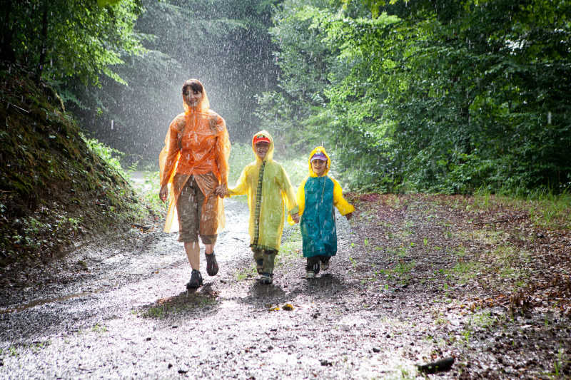下雨时在树林中行走的大人和小孩