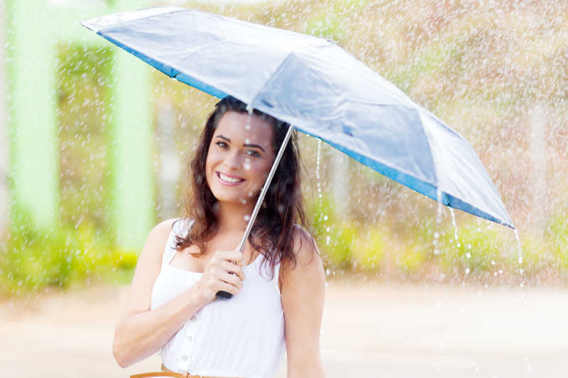 下雨时撑着蓝色雨伞的女人