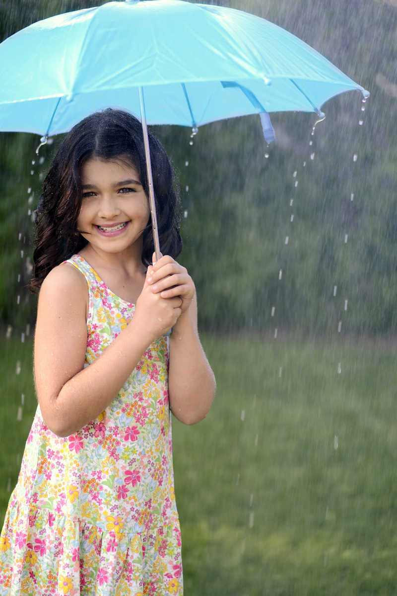 下雨时撑着蓝色雨伞的小女孩