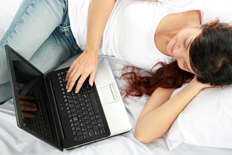 躺在床上的快乐女孩在操纵笔记本电脑