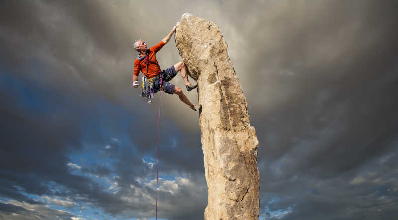 攀岩到石柱顶端的中年男性