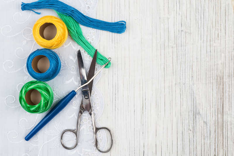 木色纹理背景下的剪刀针线等缝纫工具