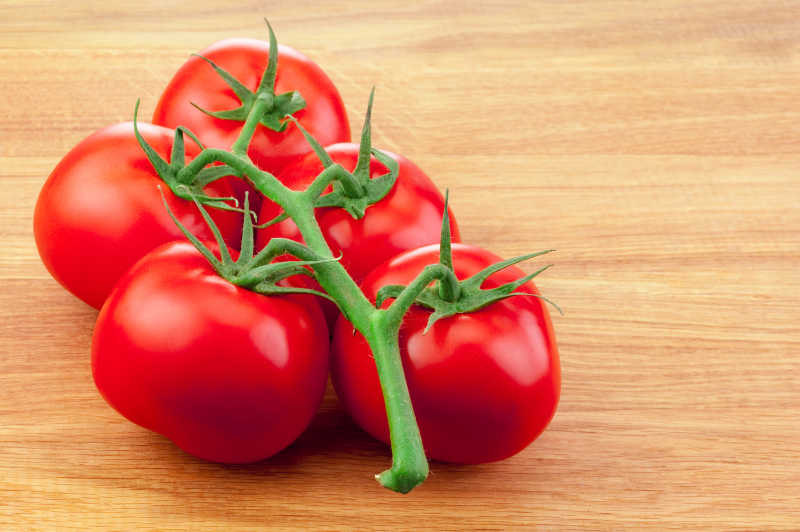 木板上带着藤蔓的几只鲜红色的西红柿