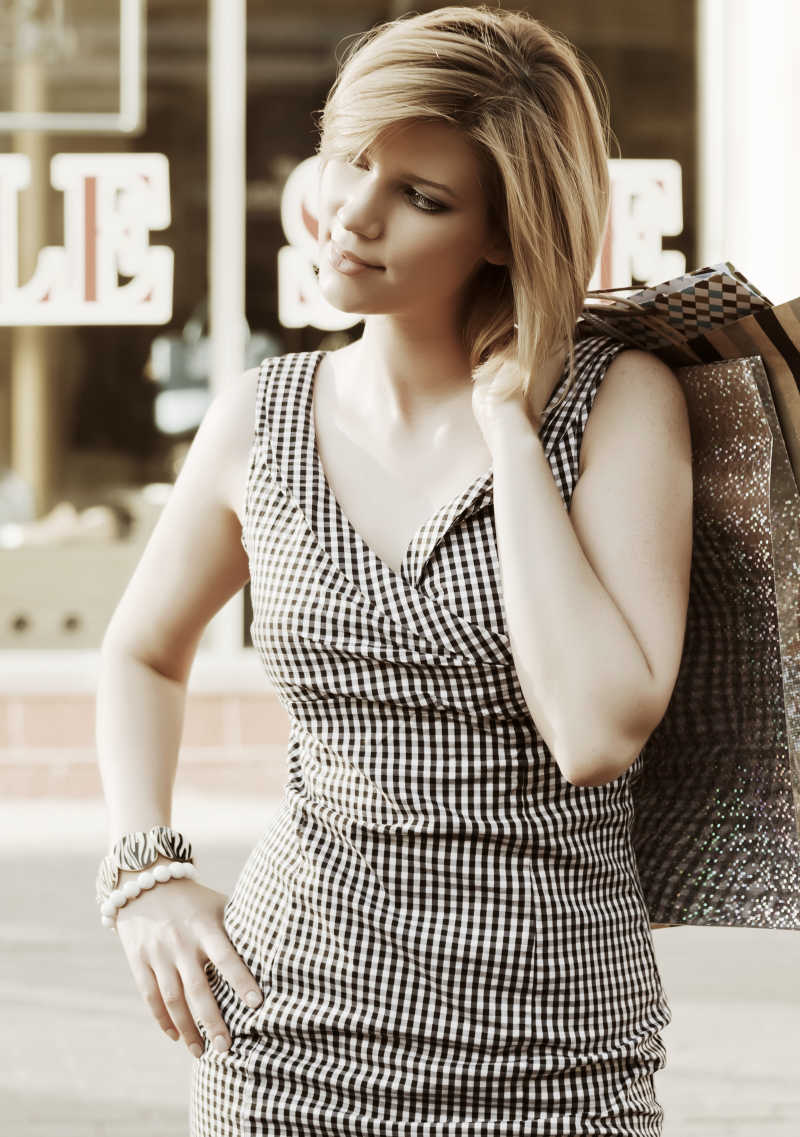 城市街道上拿着购物袋的时尚美女