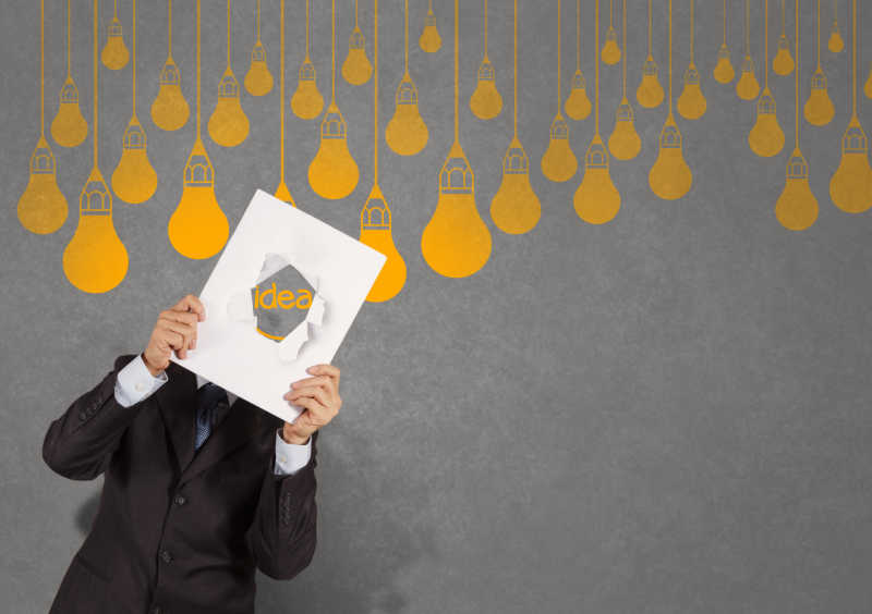 商人双手举着写着idea英文字母的纸和灯泡