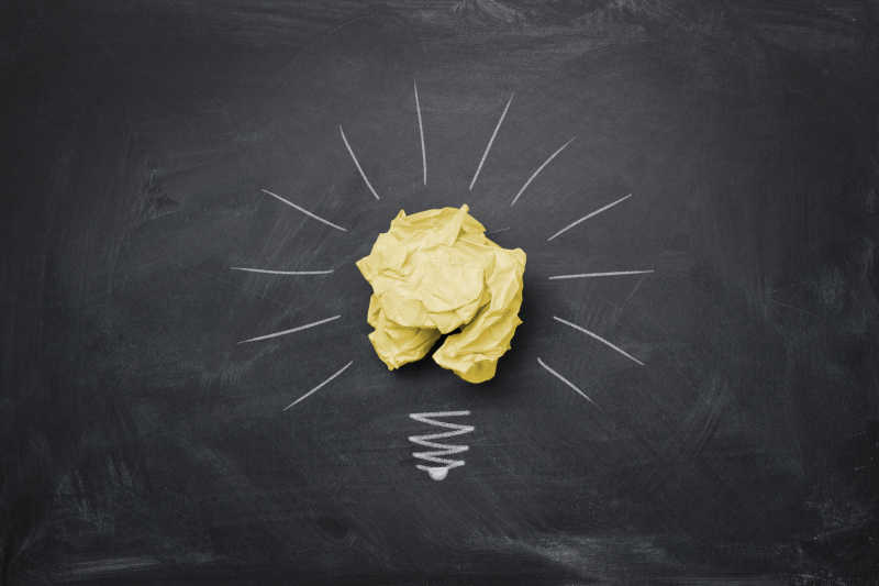 黑板上揉皱的纸张作为灯泡创意想法概念